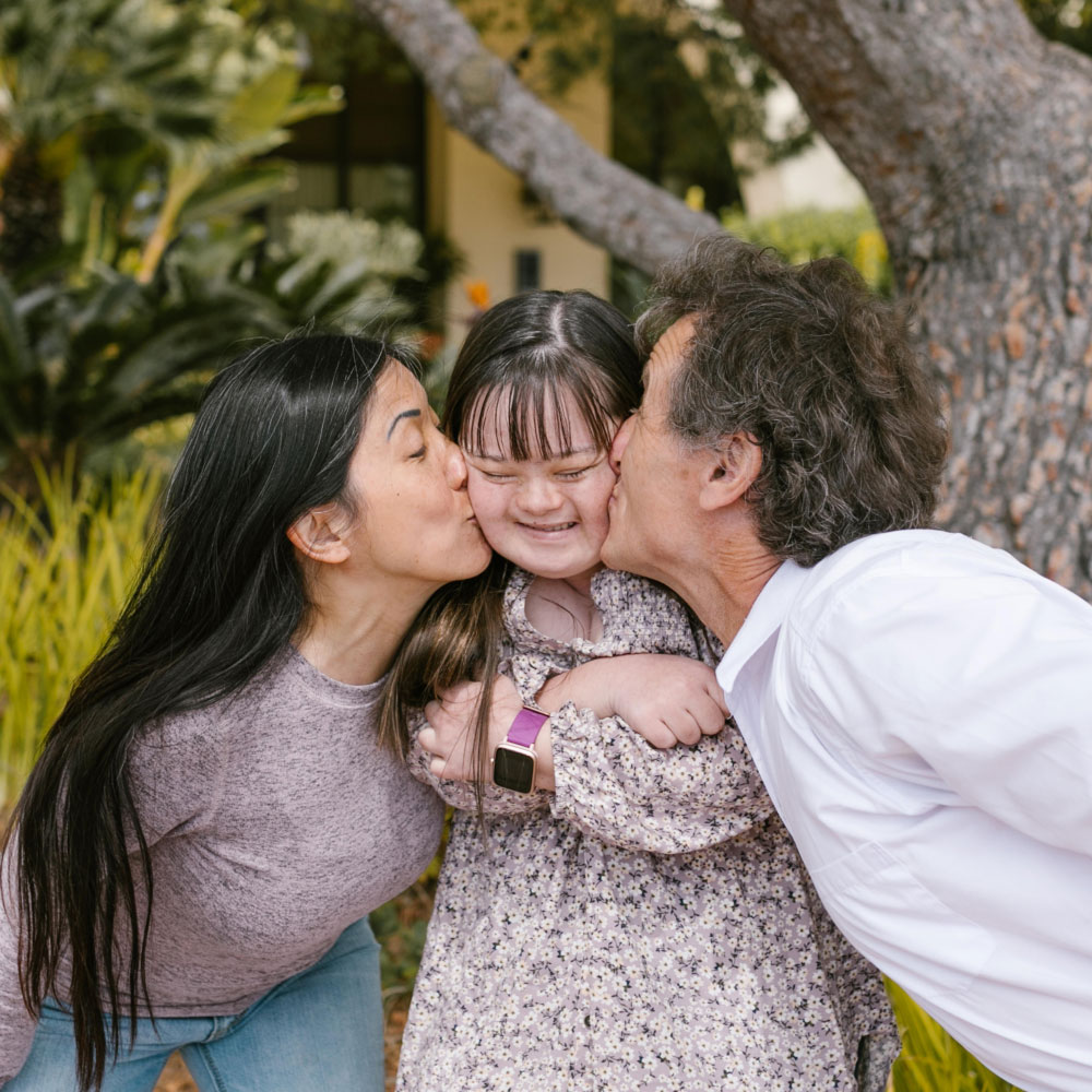 Parents kissing autistic girl